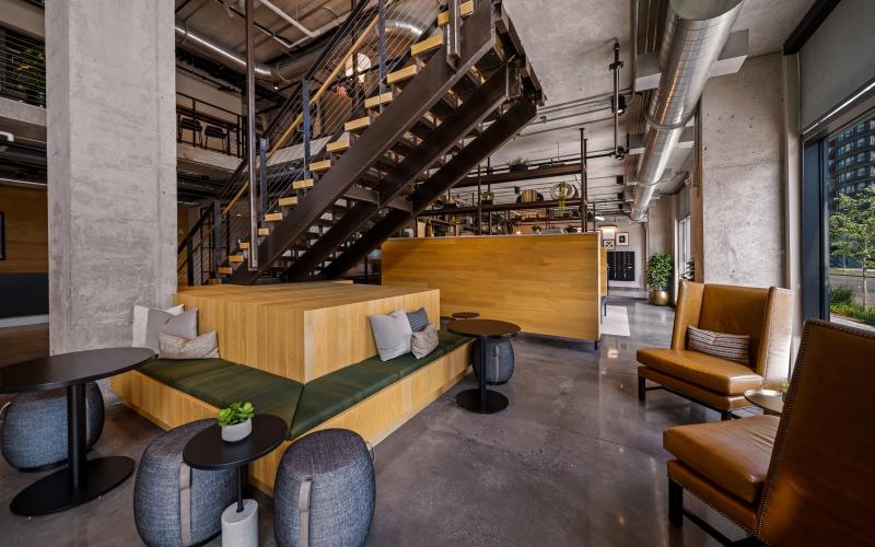 a clubhouse room with seating, tables and a staircase