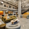 a clubhouse with couches, tables and a large staircase