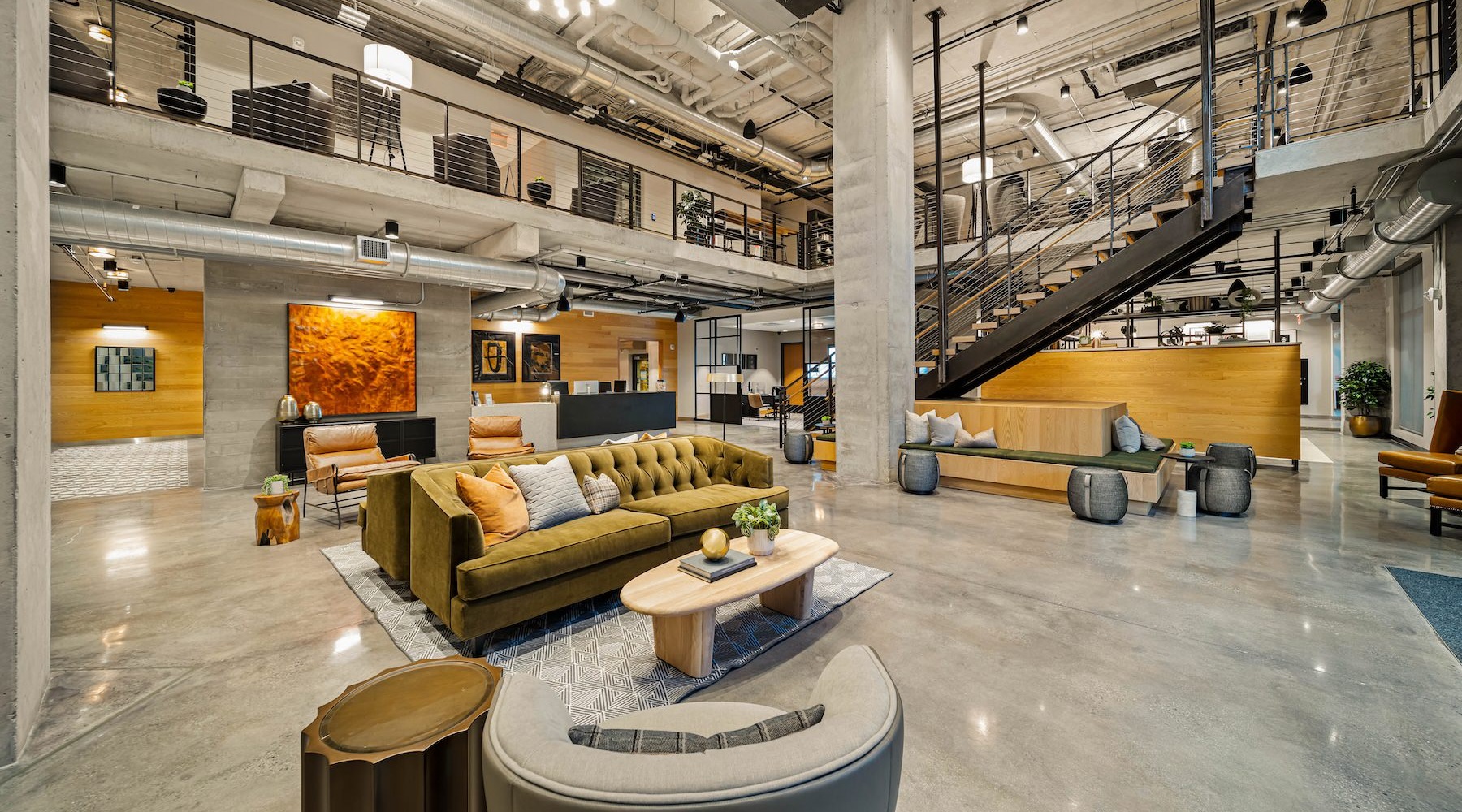 a clubhouse with couches, tables and a large staircase